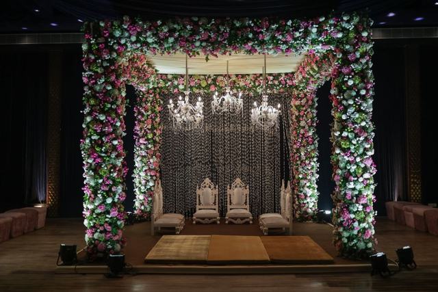 A floral wedding stage lit with chandeliers